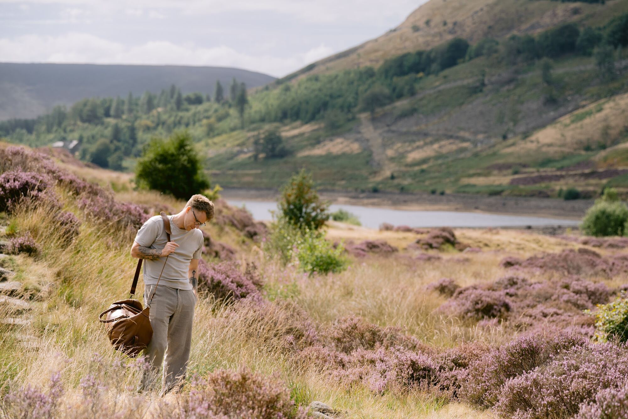 Nathan Grisdale standing in heather with his guitar