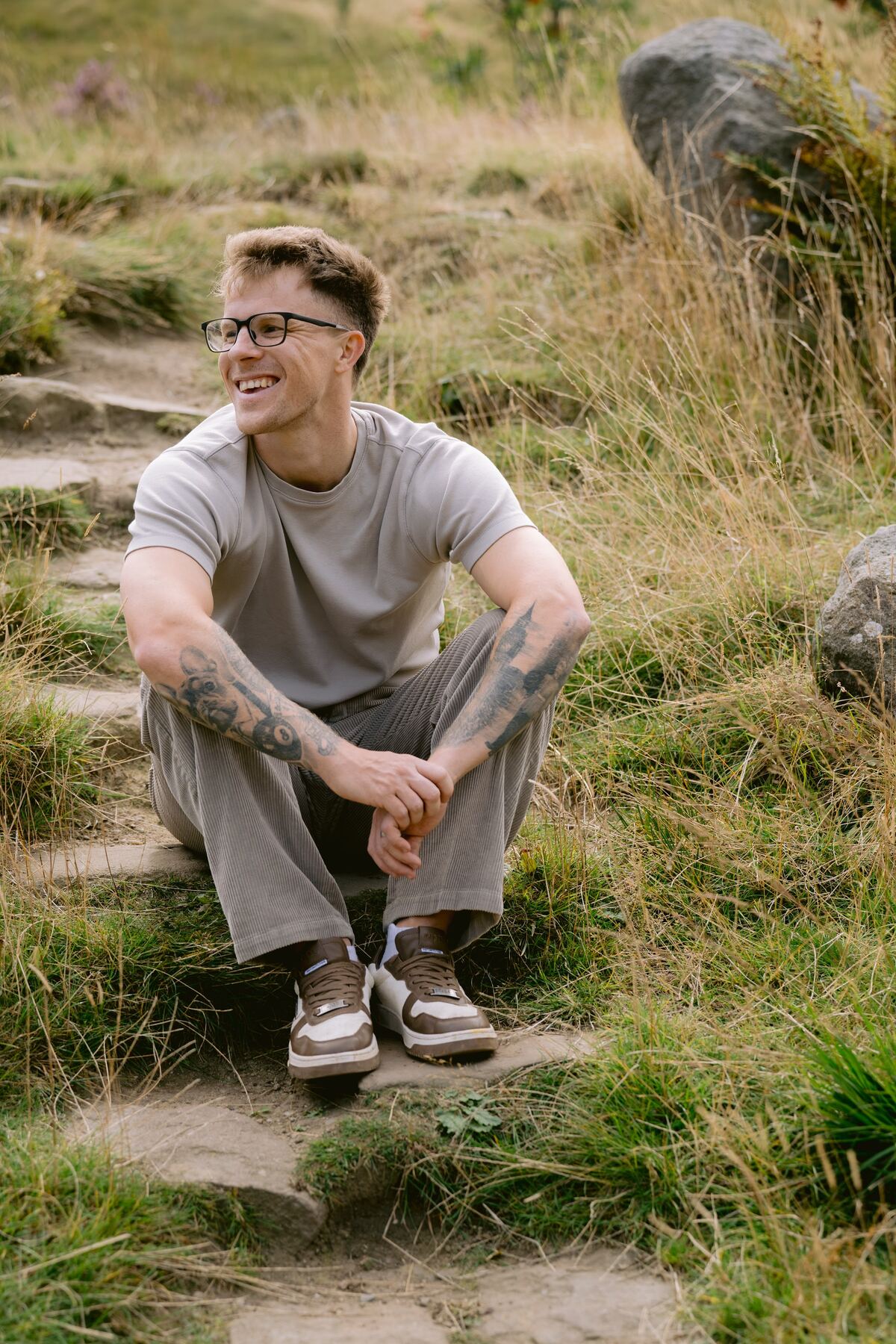 Nathan Grisdale sitting on a hillside path, laughing